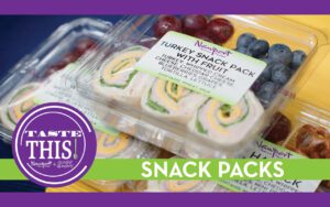 A vibrant display of snack boxes designed for grab-and-go lunches. The first box features colorful pinwheel wraps made with Boars Head turkey, cheddar cheese, cream cheese, and fresh lettuce, accompanied by a handful of juicy grapes and blueberries, or crunchy pretzels. The snack boxes are neatly arranged, highlighting their fresh ingredients and appealing presentation, perfect for busy students or adults seeking a quick, balanced meal on the go.