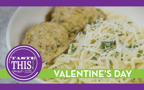 A bowl of pasta topped with shredded cheese and chopped herbs next to two chicken meatballs, with a purple and green “Taste This” graphic and the words “Valentine’s Day” across the bottom of the image.