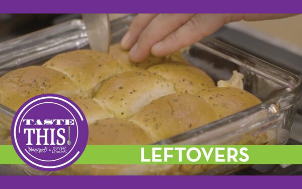 Tray of baked holiday leftover sliders made with turkey, stuffing, Swiss cheese, and cranberry BBQ sauce, topped with melted butter and seasoning, showing golden brown pull apart rolls with cheese stretching between pieces.
